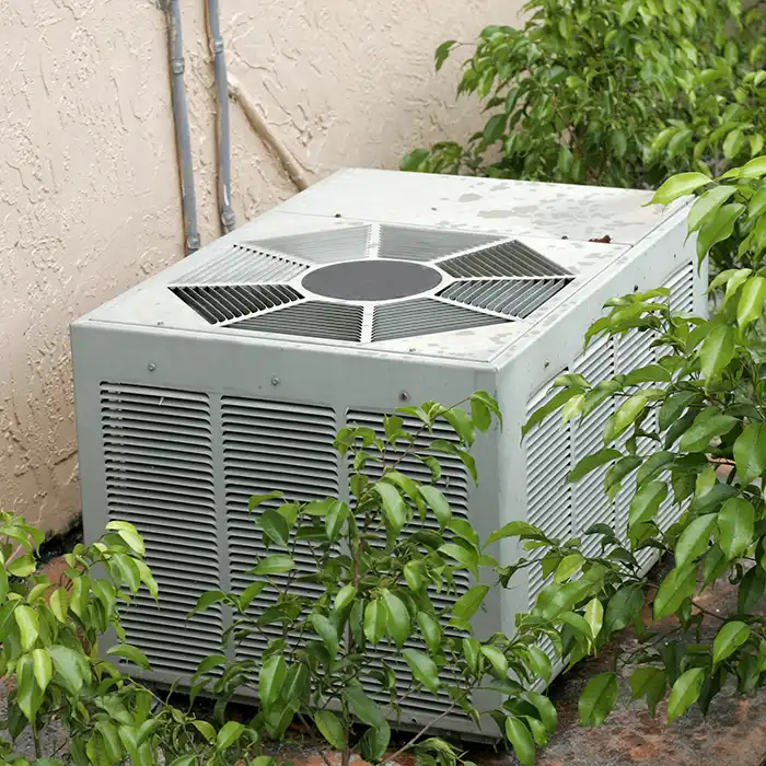 AC unit outside home behind shrubbery