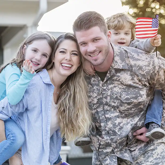 mother and military father smiling with children holding American flag